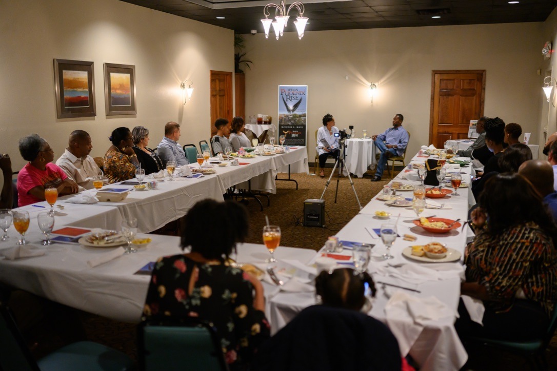 A diverse group of attendees listen during a discussion at a banquet table