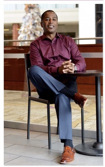 A man at a café table, showcasing a polished, professional appearance.